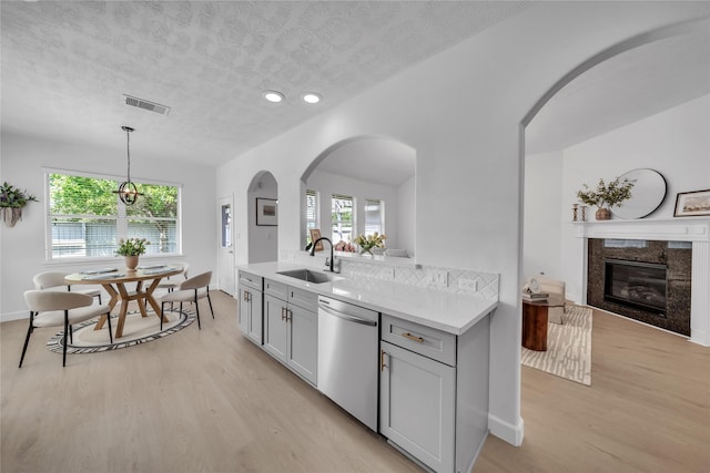 kitchen with dishwasher, a sink, light wood-style floors, light countertops, and a textured ceiling