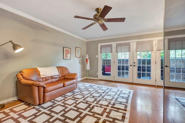 living area with wood finished floors, plenty of natural light, a ceiling fan, and crown molding
