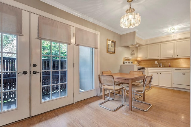 dining area with crown molding, light wood-style floors, and a chandelier