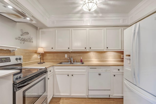 kitchen featuring white appliances, a sink, wall chimney exhaust hood, light countertops, and white cabinetry
