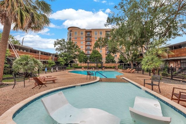 community pool featuring fence and a patio