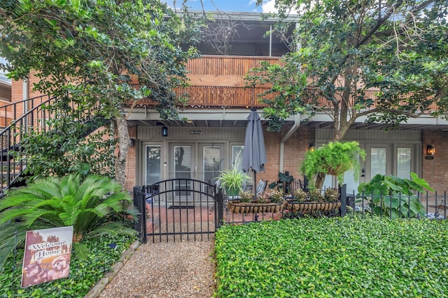 view of exterior entry with brick siding, french doors, and a gate
