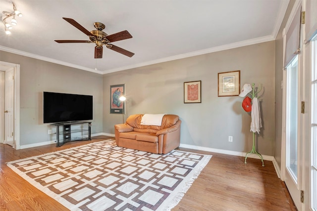 living area featuring wood finished floors, baseboards, ceiling fan, and crown molding