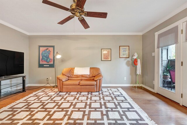 sitting room with wood finished floors, crown molding, baseboards, and ceiling fan