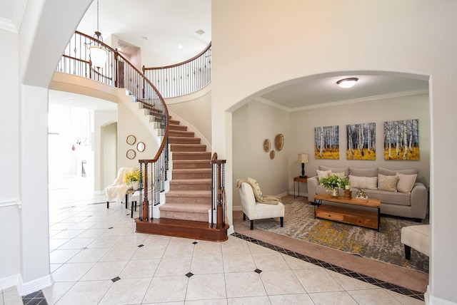 5530 Riverstone Crossing Dr, Sugar Land, TX 77479 - tiled living room with arched walkways, a high ceiling, ornamental molding, stairs, and baseboards