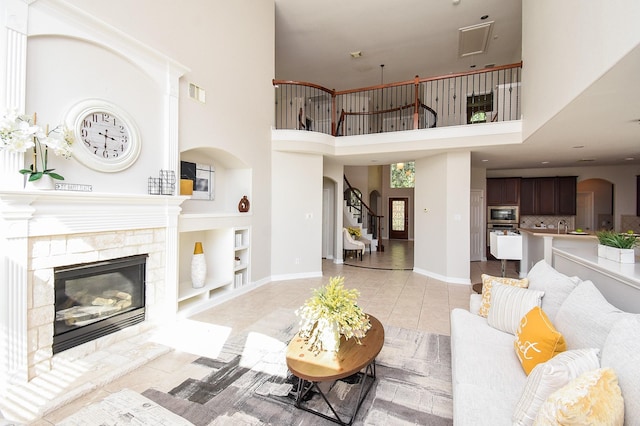 5530 Riverstone Crossing Dr, Sugar Land, TX 77479 - living room with a fireplace, arched walkways, light tile patterned floors, stairs, and a high ceiling