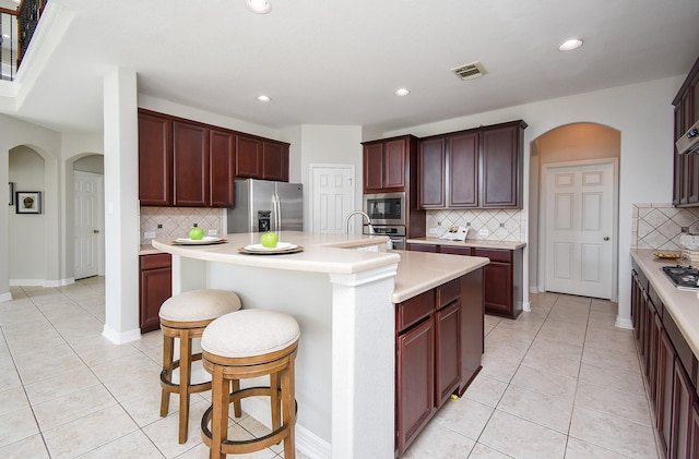 5530 Riverstone Crossing Dr, Sugar Land, TX 77479 - kitchen with stainless steel appliances, arched walkways, tasteful backsplash, light tile patterned flooring, and recessed lighting