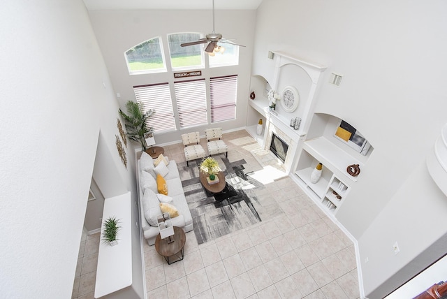 5530 Riverstone Crossing Dr, Sugar Land, TX 77479 - tiled living room with high vaulted ceiling, a ceiling fan, built in shelves, and a fireplace with flush hearth