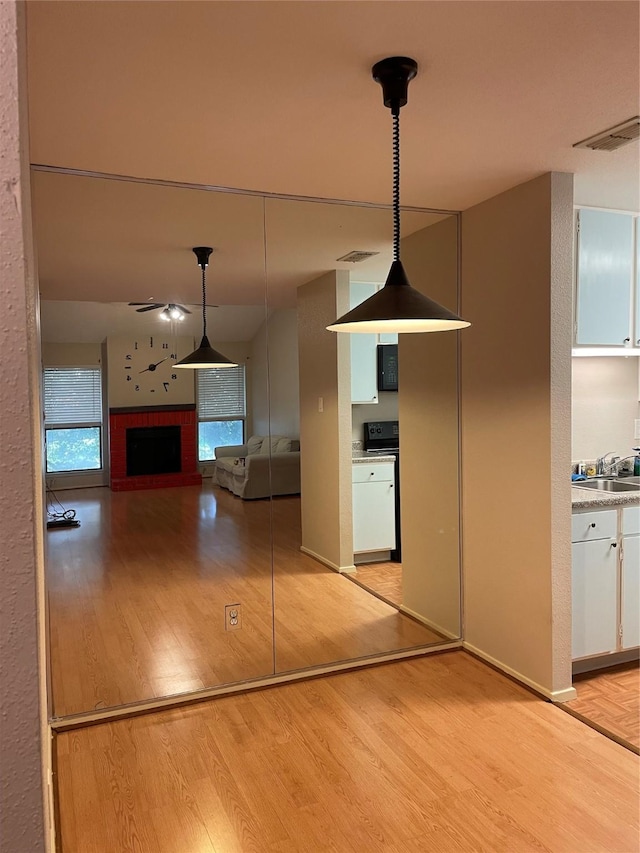 7950 N Stadium Dr Unit 210, Houston, TX 77030 - kitchen with light wood-style flooring, white cabinetry, range, ceiling fan, and hanging light fixtures