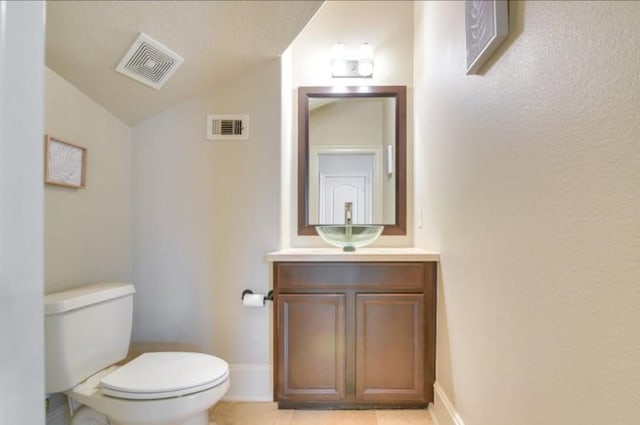 bathroom featuring vaulted ceiling, toilet, vanity, tile patterned flooring, and baseboards