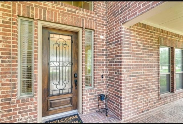 doorway to property featuring brick siding