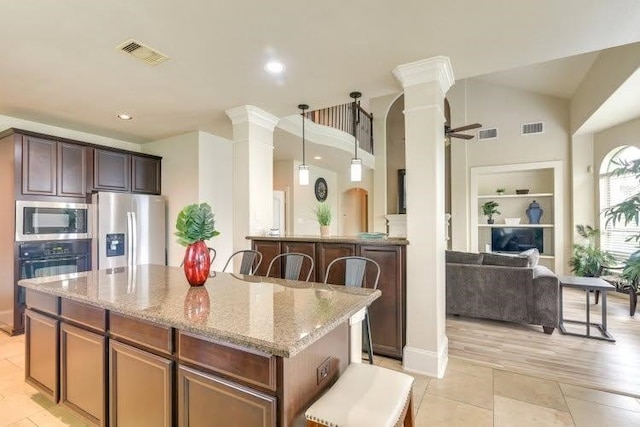 kitchen with ornate columns, stainless steel appliances, light stone countertops, recessed lighting, and a high ceiling