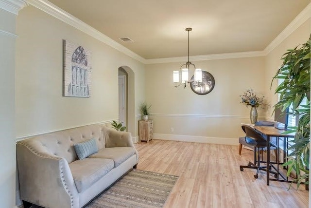 living area with arched walkways, wood finished floors, a chandelier, crown molding, and baseboards