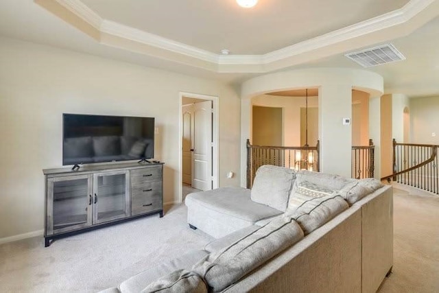 living room featuring light carpet, a raised ceiling, crown molding, arched walkways, and baseboards