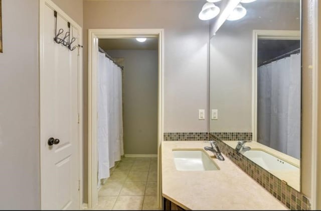 full bath with vanity, tile patterned flooring, and baseboards