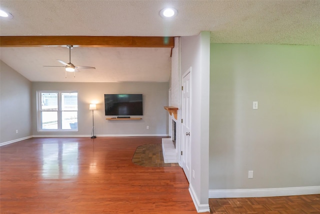 unfurnished living room featuring ceiling fan, a textured ceiling, a brick fireplace, baseboards, and beam ceiling