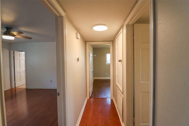 corridor featuring wood finished floors and baseboards