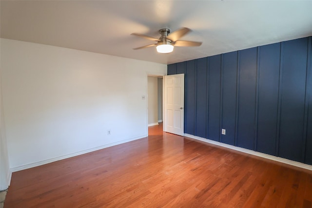 spare room with ceiling fan, wood finished floors, and baseboards