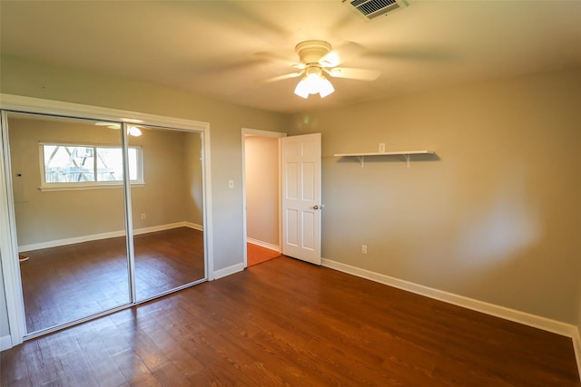 unfurnished bedroom with dark wood-style floors, a closet, baseboards, and ceiling fan