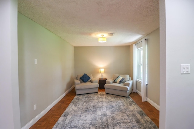 living area with a textured ceiling and baseboards
