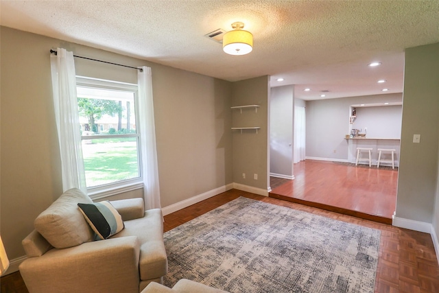 sitting room with a textured ceiling, baseboards, and recessed lighting