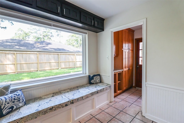 mudroom featuring light tile patterned floors, healthy amount of natural light, and a wainscoted wall