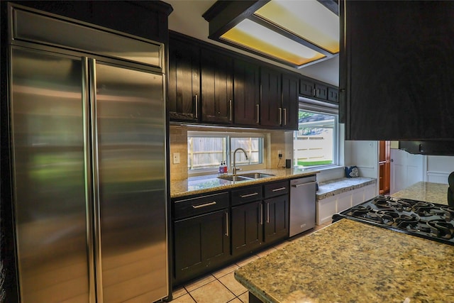 kitchen featuring appliances with stainless steel finishes, a sink, light tile patterned flooring, light stone counters, and extractor fan