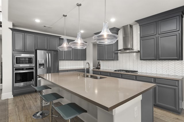 12510 Grayton Dr, Texas City, TX 77568 - kitchen with stainless steel appliances, wall chimney range hood, a sink, backsplash, and a center island with sink