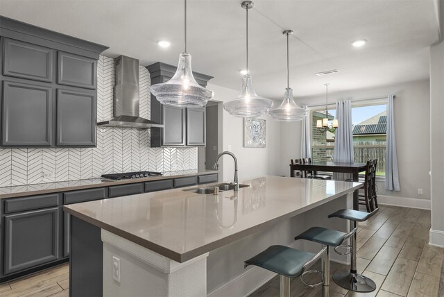12510 Grayton Dr, Texas City, TX 77568 - kitchen with wall chimney range hood, a sink, tasteful backsplash, stainless steel gas stovetop, and a center island with sink