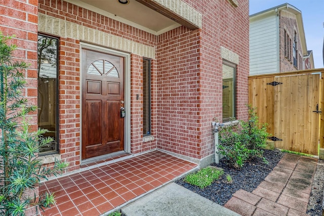 entrance to property with brick siding and fence