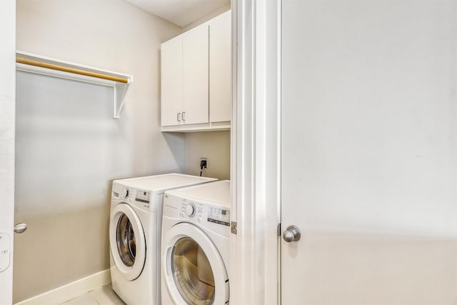 laundry area featuring cabinet space, separate washer and dryer, baseboards, and light tile patterned flooring