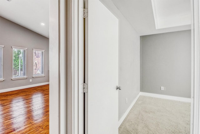 hallway featuring baseboards, lofted ceiling, and recessed lighting