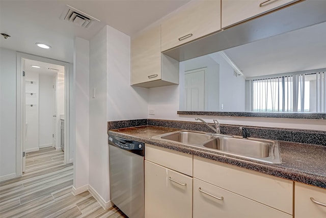 kitchen featuring dishwasher, a sink, baseboards, dark countertops, and light wood-type flooring