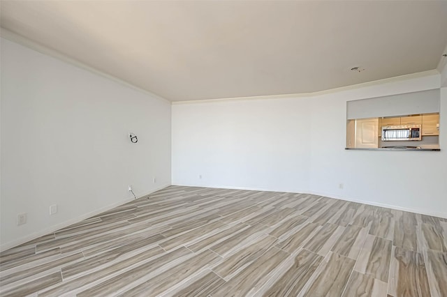 unfurnished room with light wood-style flooring, baseboards, and ornamental molding