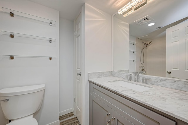 bathroom featuring toilet, vanity, and a shower