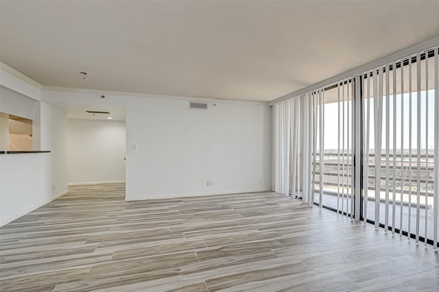 unfurnished living room with light wood-type flooring and a wall of windows