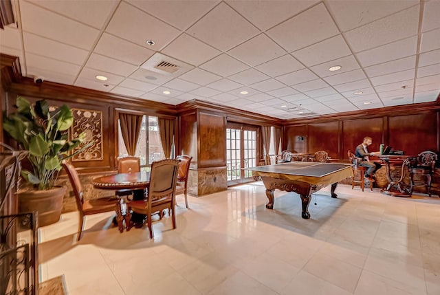 recreation room featuring billiards table, plenty of natural light, crown molding, wood walls, and a drop ceiling