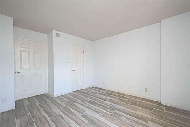 spare room featuring wood finish floors and baseboards