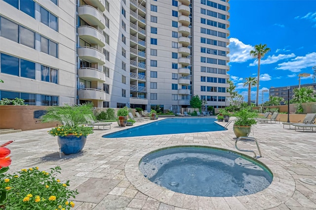 community pool with a hot tub and a patio area
