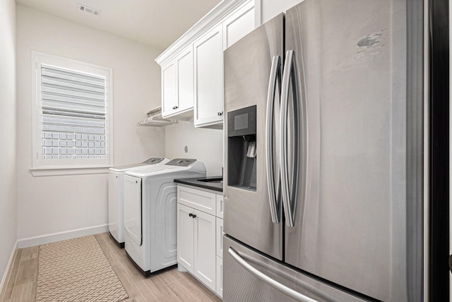 1703 Madera Oaks Ct, Conroe, TX 77304 - laundry area with separate washer and dryer, light wood finished floors, and cabinet space