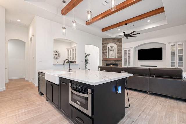 1703 Madera Oaks Ct, Conroe, TX 77304 - kitchen with dark cabinetry, a ceiling fan, open floor plan, a fireplace, and beam ceiling