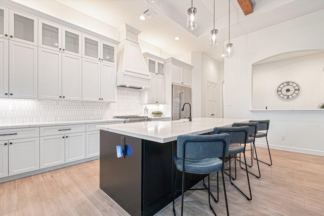 1703 Madera Oaks Ct, Conroe, TX 77304 - kitchen with custom exhaust hood, stainless steel appliances, a center island with sink, backsplash, and a kitchen breakfast bar