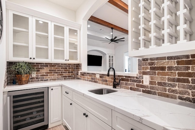 1703 Madera Oaks Ct, Conroe, TX 77304 - kitchen featuring wine cooler, tasteful backsplash, light stone counters, white cabinetry, and beamed ceiling