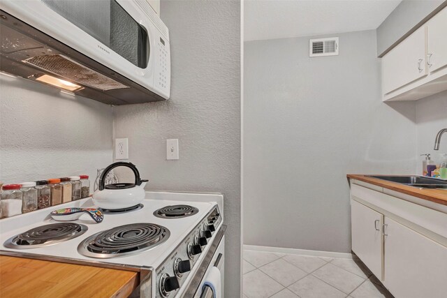 3131 Cummins St Unit 94, Houston, TX 77027 - kitchen featuring white microwave, range with electric cooktop, a sink, light tile patterned floors, and white cabinetry