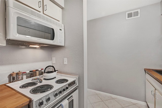 3131 Cummins St Unit 94, Houston, TX 77027 - kitchen featuring white appliances, baseboards, light tile patterned floors, and white cabinets