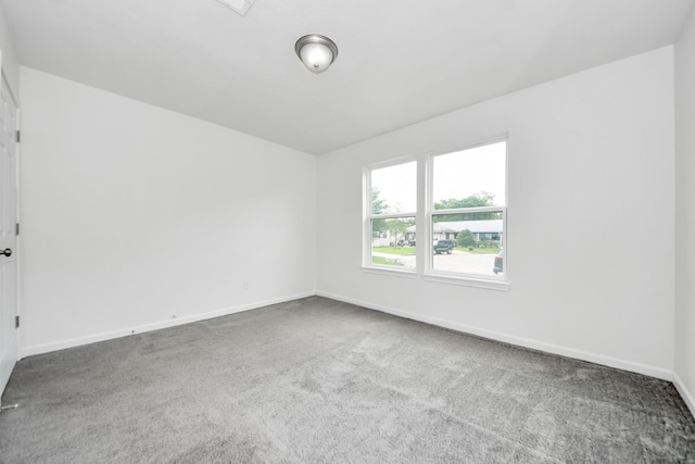 carpeted empty room featuring baseboards