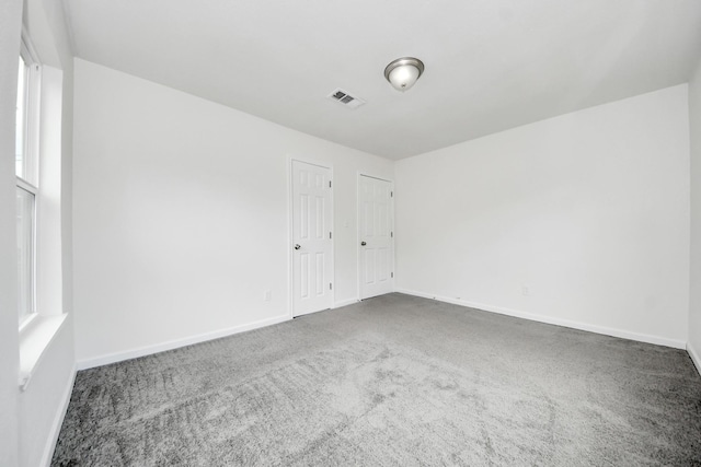 empty room with dark colored carpet and baseboards