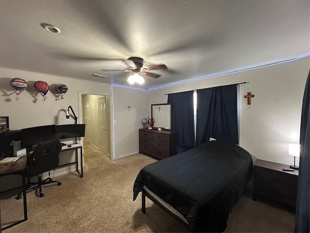 bedroom with an office area, light carpet, a textured ceiling, and ceiling fan