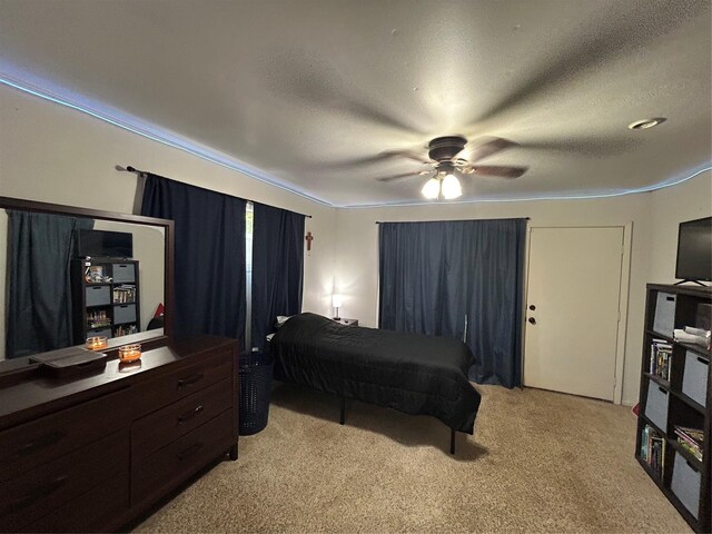 bedroom featuring light carpet, a textured ceiling, and ceiling fan