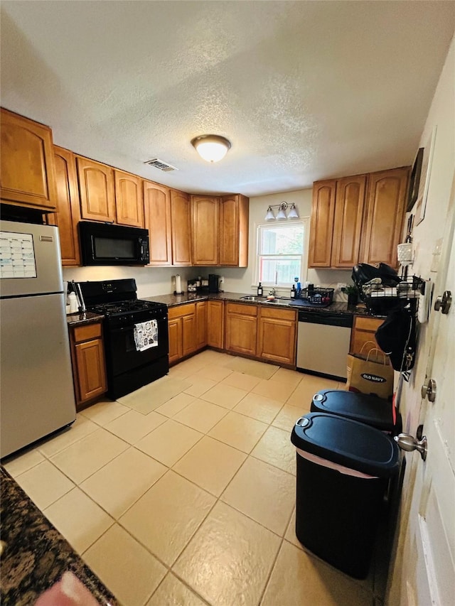 kitchen featuring black appliances, brown cabinetry, light tile patterned floors, and a textured ceiling